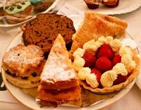Photograph of cream cakes, strawberries and scones on a plate